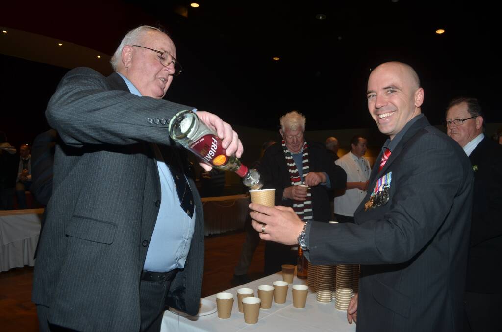WARM UP: RSL sub branch president Lindsay Wright pours a shot of rum in the Adam Tudor's coffee at the breakfast after the dawn service. Photo: CLARE COLLEY.