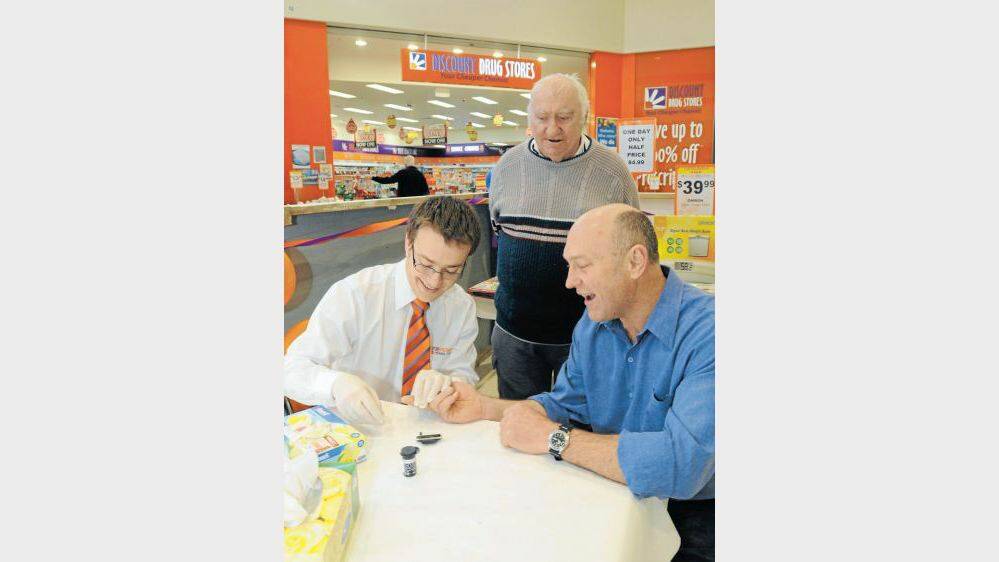 North Orange pharmacist Tim Denham helps councillor Scott Munro through a diabetes test, with type 2 diabetic Alf Brodie looking on. Photo: STEVE GOSCH 0717sgdiabetes1