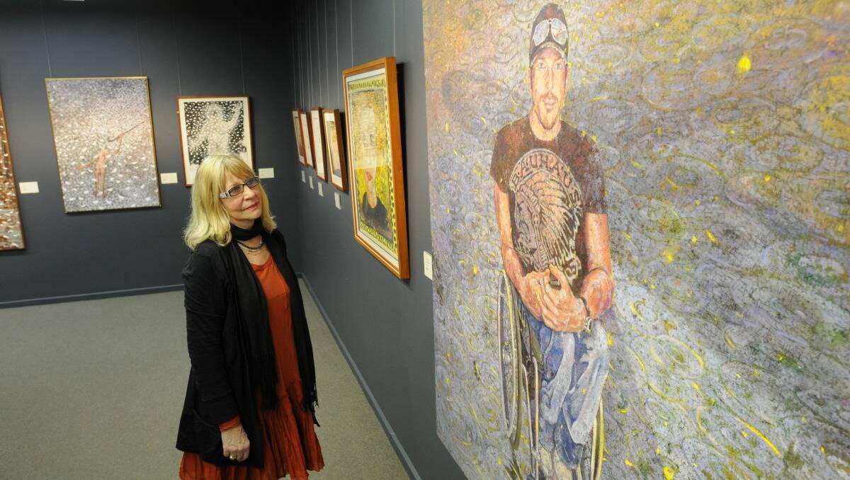 Orange Regional Gallery's Brenda Gray with a portrait of Kurt Feanley by artist Martin Coyte. The artwork features is one of two new exhibitions to open tonight. Photo: STEVE GOSCH 0822sgart2