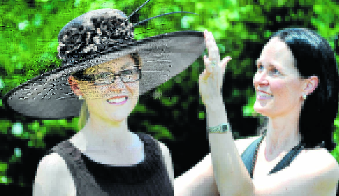 HOT FASHION: Milliner Fiona Schofield helps Trudy Glasgow try on race fashion hats in the lead-up to Saturday's Orange picnic races.  Photo: STEVE GOSCH 0116sghat1