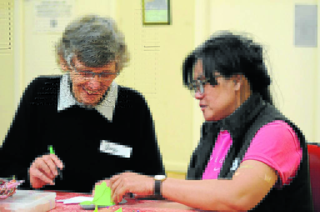 MAKING FRIENDS Volunteer June Tupper helps Corazon Lee at a sewing bee on Thursday. Photo: STEVE GOSCH
