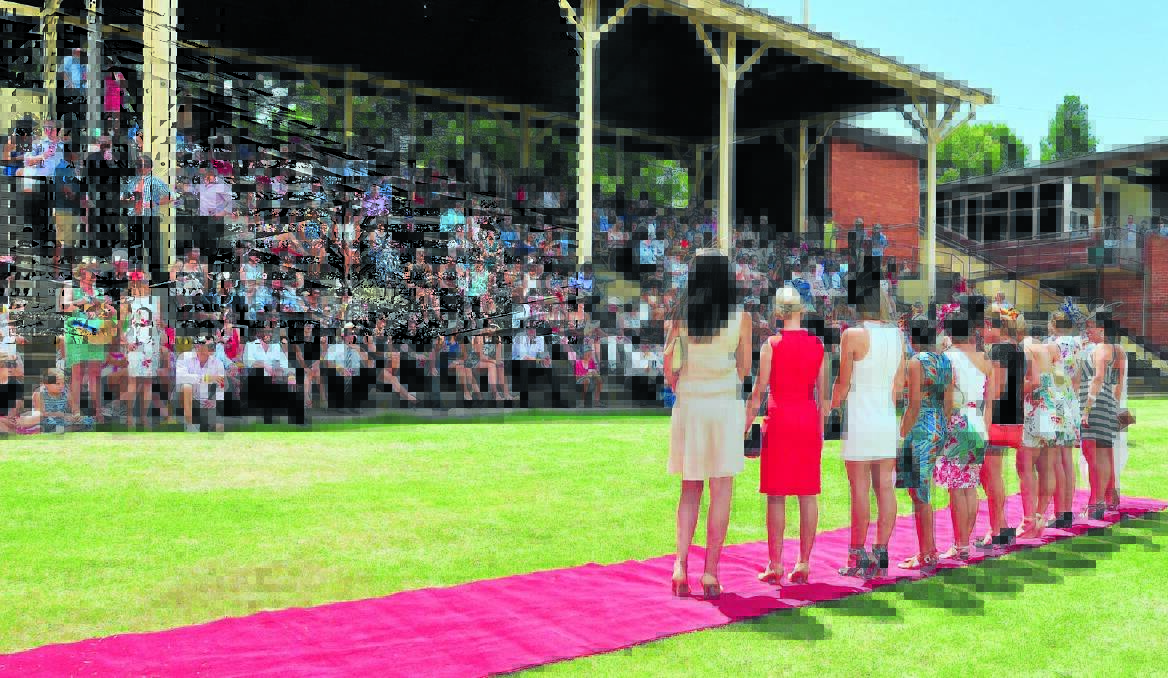 BACKS ON TRACK: Fashions on the field contestants parade before a packed grandstand at the picnic races. Photo: JUDE KEOGH 0118racessoc3