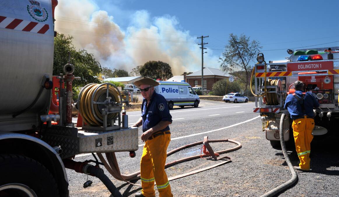 WHERE THERE’S SMOKE: Rural Fire Service volunteers filling up their trucks with water in the main street of Wattle Flat as a bushfire was burning just a kilometre away early yesterday afternoon.  Photo: ZENIO LAPKA 013114zfire13