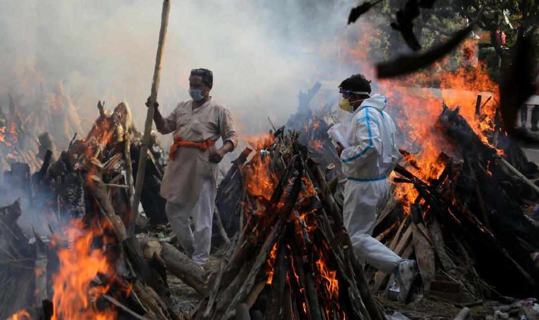 Relatives stand next to the burning funeral pyres of those who died due to COVID-19 at Ghazipur cremation ground in New Delhi. Picture: Getty Images