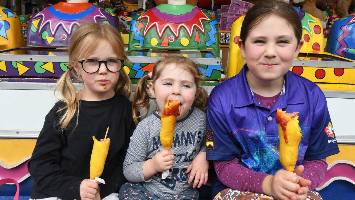DOWN DOG: Eliza, Louanna and Josie Culverson tuck into some traditional show-time tucker at the 150th Orange Show on Saturday. Photo CARLA FREEDMAN