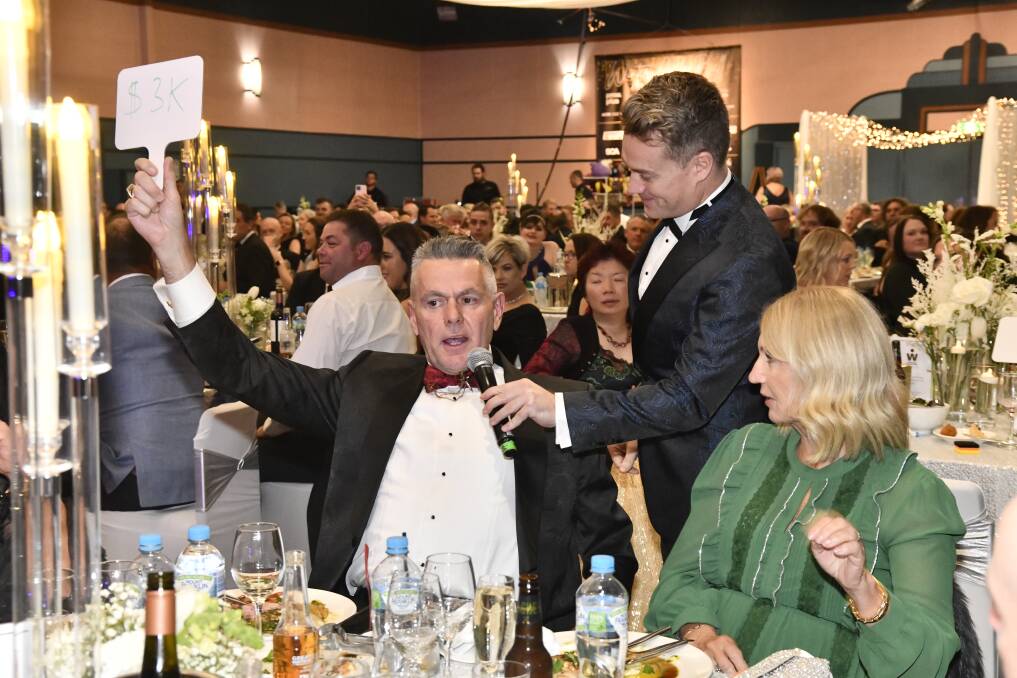 An attendee places a $3000 bid on July 15 at the RMHC Central West annual gala ball, with presenter Grant Denyer supporting the auction process. Picture by Jude Keogh.