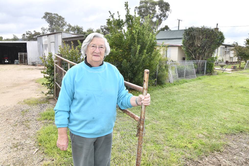 Eugowra's Mavis Cross holds onto the gate at the side of her property on May 9; the same fixture she clung onto while her son George waded through flood water to reach her. Picture by Jude Keogh.