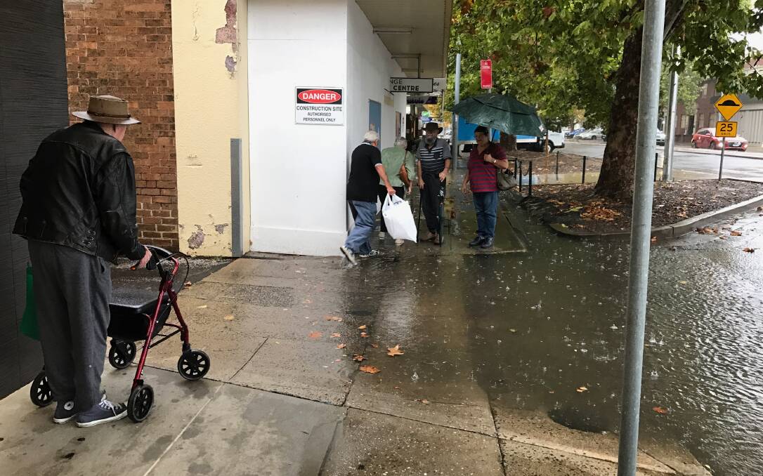 A WELCOME HINDRANCE: Pedestrians trying to navigate a semi-flooded driveway on Anson Street during Friday morning's rain. Photo: CARLA FREEDMAN
