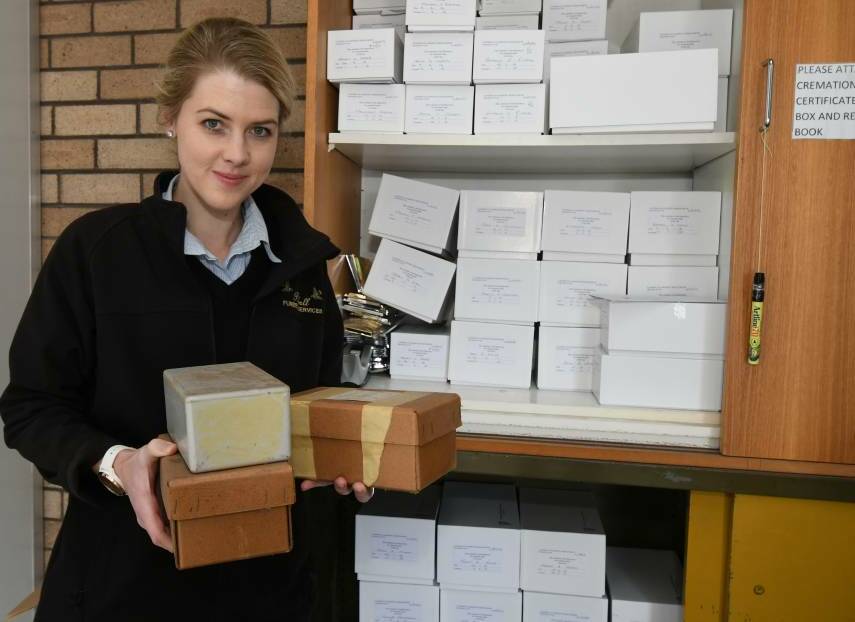 ASHES TO ASHES: Funeral director Jasmine Wilkins holds some of the oldest boxes of remains stored in cupboards at the funeral parlour. Photo: JUDE KEOGH 0906jkashes1