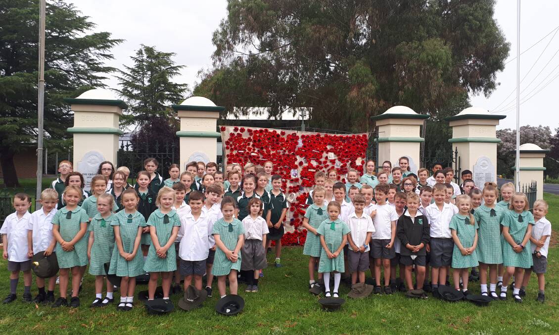 PAYING THEIR RESPECTS: Cudal Public School students in front of the poppy blanket at the viallge's war memorial. Photo: SUPPLIED