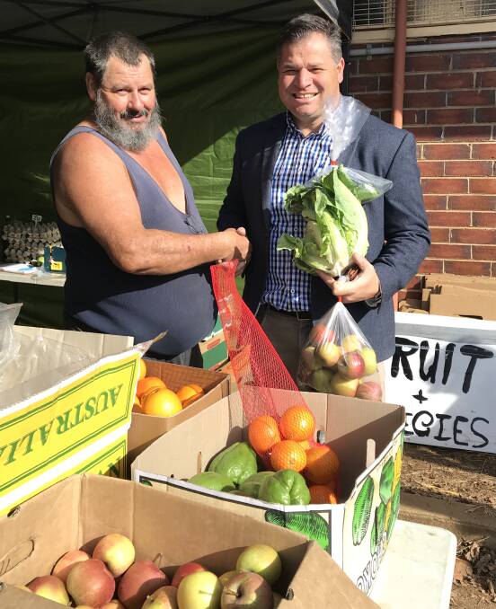 SHOP LOCAL: Local producer Neil Clarkson sells some fruit and vegetables from his road-side stall to member for Orange Philip Donato. Photo: CONTRIBUTED