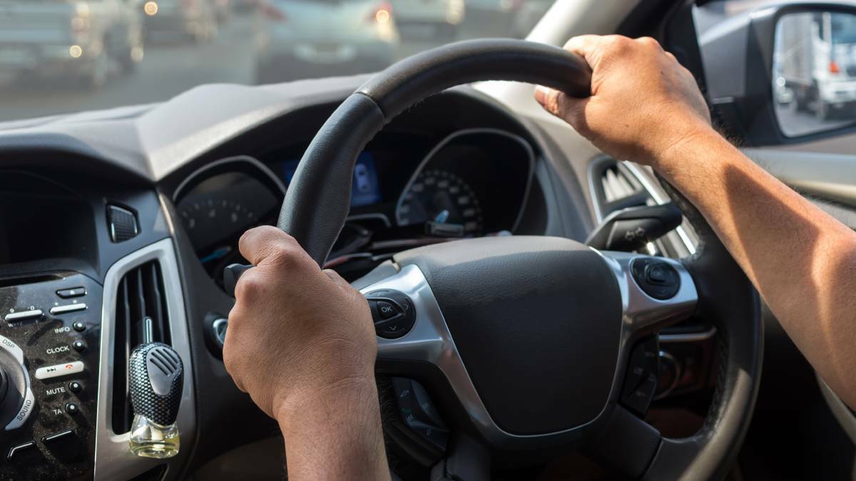 A person with their hands placed on a vehicle's steering wheel. File picture