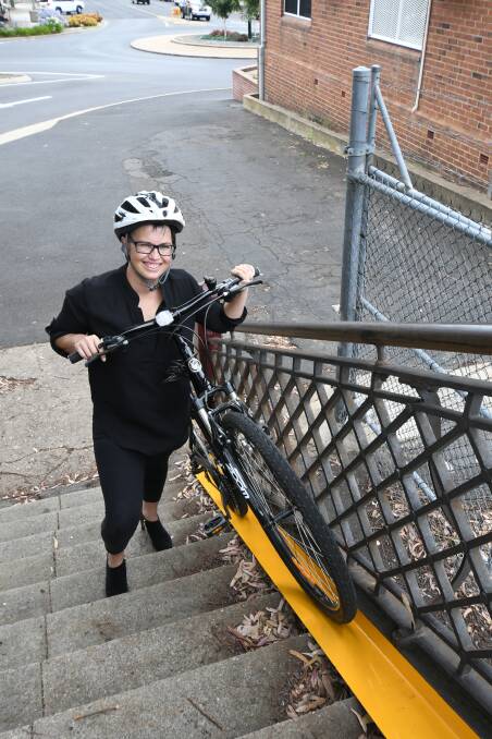 UP AND OVER: Hayley Barrett takes her bicycle over the footbridge near Orange Railway Station. Photo: JUDE KEOGH 0112jkramp2