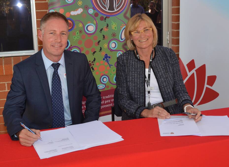 DOTTED LINE: Western NSW Local Health District chief exective Scott McLachlan and Western NSW Health Research Network chair Catherine Hawke sign a three-year agreement on Tuesday. Photo: DANIELLE CETINSKI