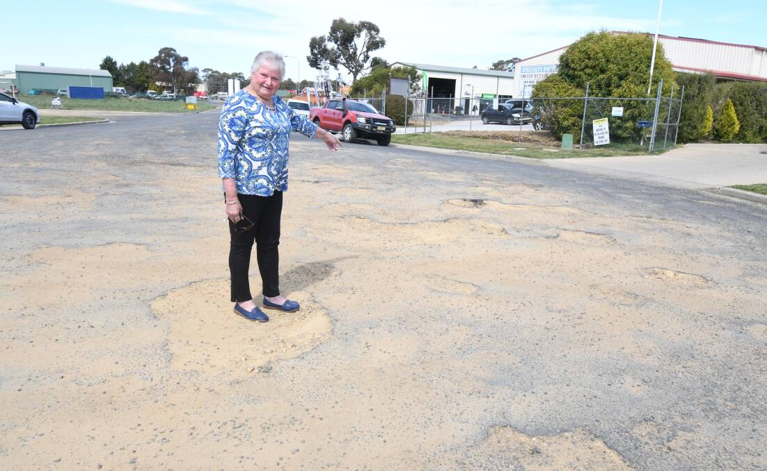 ROAD TO RUIN: Orange motorist Eileen Ford stands in one of the many potholes on Scott Place south of Orange. Photo: JUDE KEOGH 1004jkpotholes1