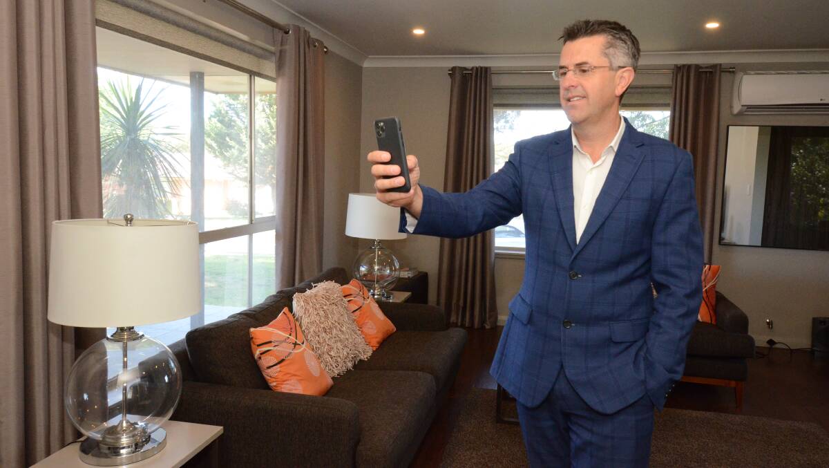 ARMCHAIR OPENS: Estate agent Ash Brown videos the inside of a house for sale in Taronga Avenue for a Facebook live show. Photo: JUDE KEOGH