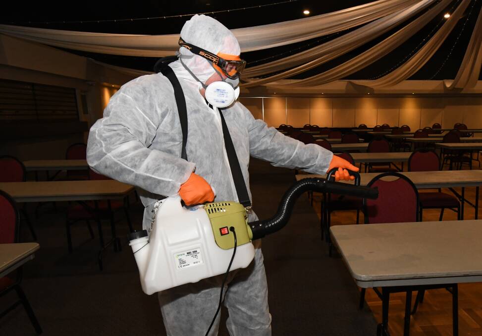 VIRUS WEAPON: Stuart Vaughan uses the fogging machine to clean tables in the Orange Ex-Services' Club. Photo: JUDE KEOGH