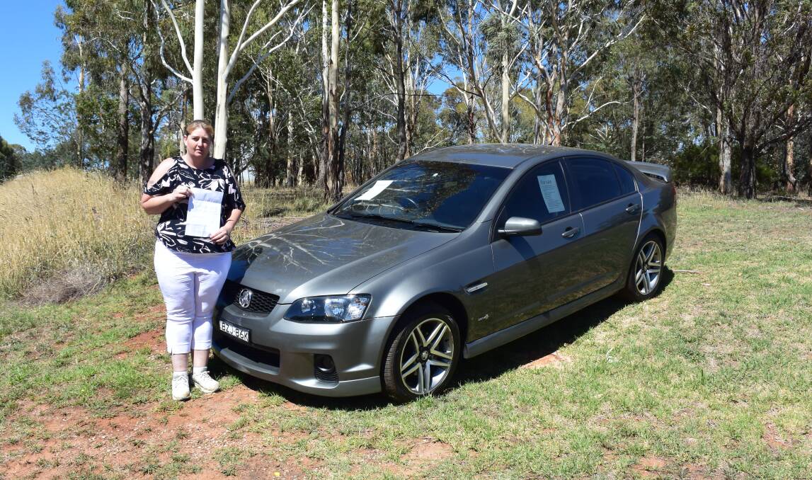 UPSET: Janet Sutherland with the car she is trying to sell on the roadside and the warning letter left on her windscreen. Photo: DAVID FITZSIMONS 0215dfjanet3