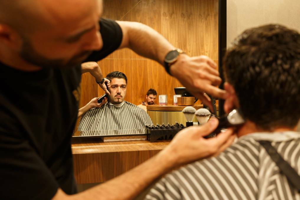 TOP CUT: Mike Helwe gives Newcastle Jets football player Dimi Petratos a trim at a Barber Industries shop near Newcastle. Photo: Max Mason-Hubers, Newcastle Herald