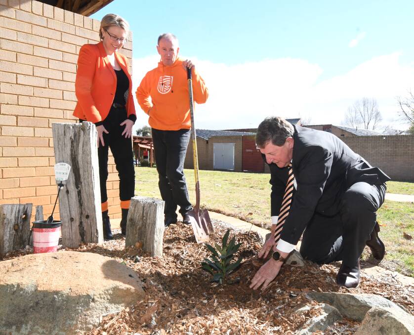 HANDS ON: CSU's Julia Andrews and Paul Dowler watch as Orange mayor Reg Kidd plants the tree. Photo: JUDE KEOGH