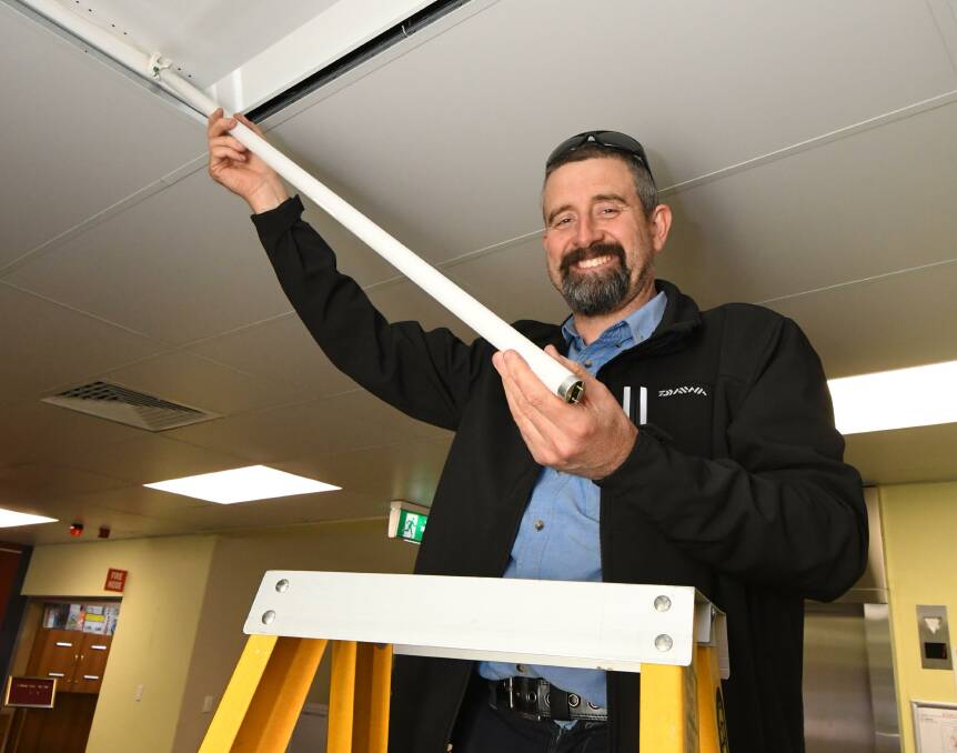 REPLACEMENT: Council electrician Ben Brennan replaces an old-style light in the council offices. Photo: JUDE KEOGH
