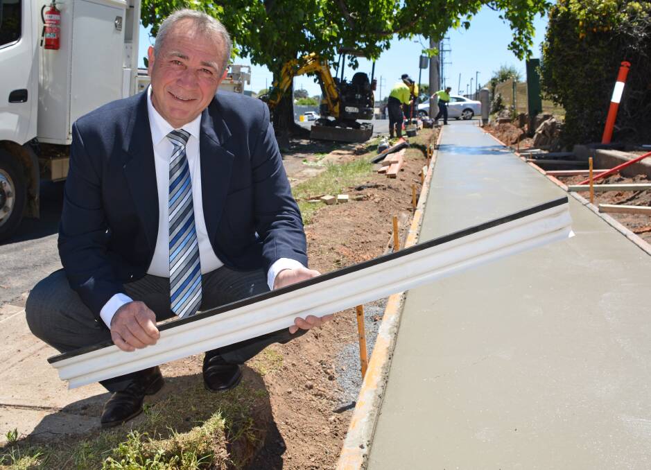 HELPING HAND: Council's infrastructure committee chair Cr Sam Romano with a hinge used to reduce tree root damage on the city's new footpaths. Photo: Supplied