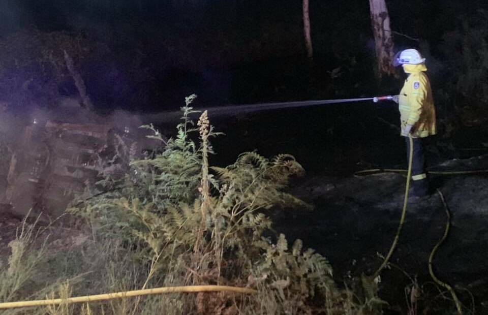 FOREST FIRE: A firefighter extinguishes the smouldering wreck on Monday night. Photo: Facebook