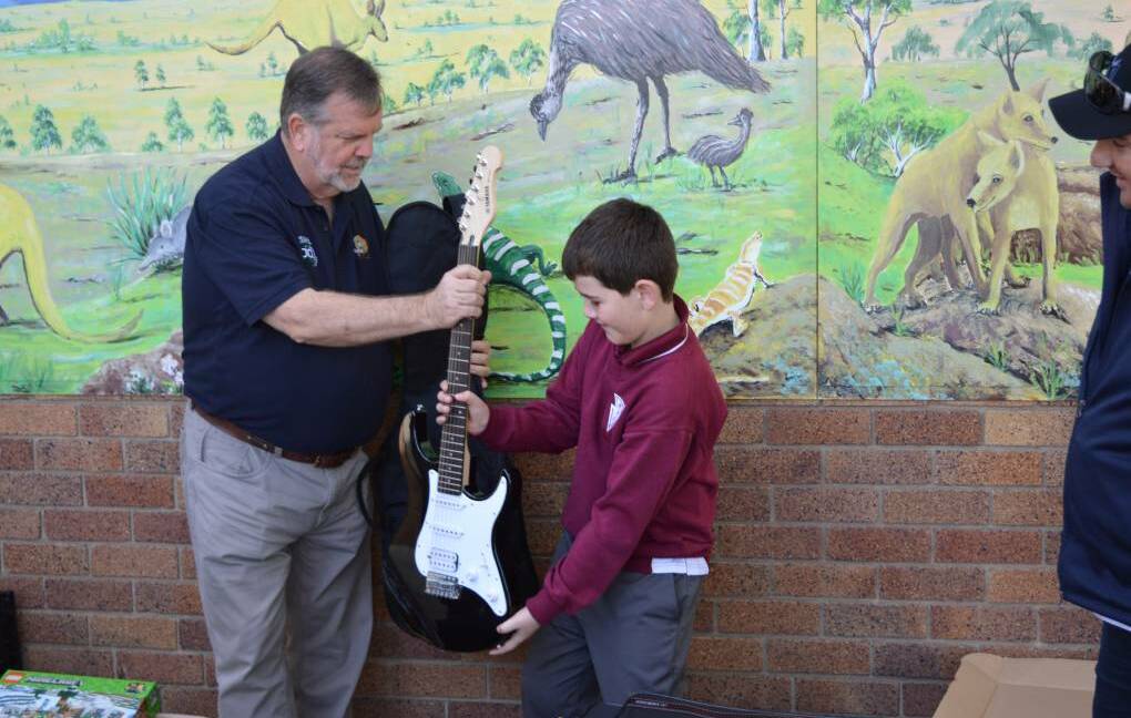 GIFT: Rural Aid's Wayne Thomson donates a guitar to a NSW school last month. Photo: Maitland Mercury