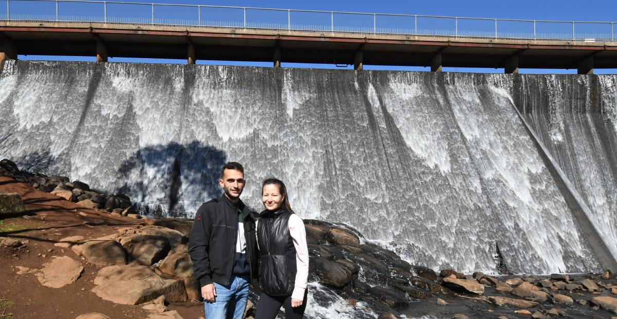 ATTRACTION: Sydney tourists Luigi Siclari and Zhanna Batyrkulova at Lake Canobolas on Monday as water gushes over the spillway from the full lake. Photo: CARLA FREEDMAN