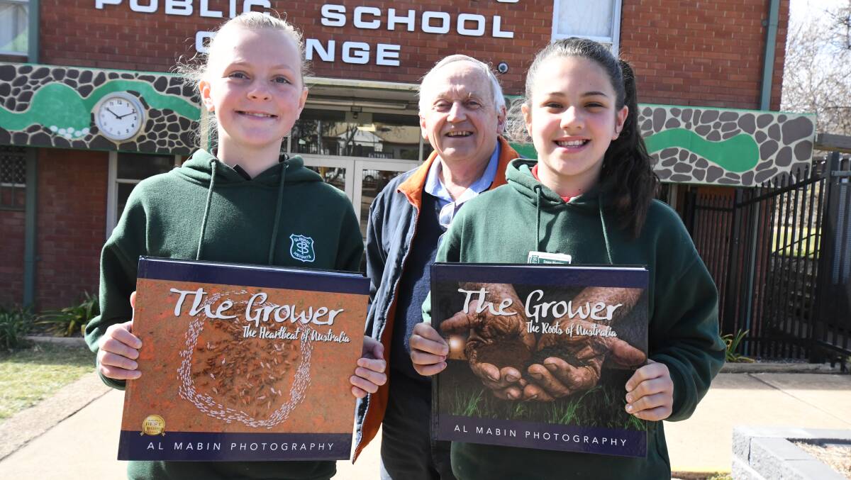GIFTS: Glenroi Heights Public School students Bianca Howell and Emma Manning with Phillip Schwebel of Collins Booksellers. Photo: JUDE KEOGH 0820jkbooks1