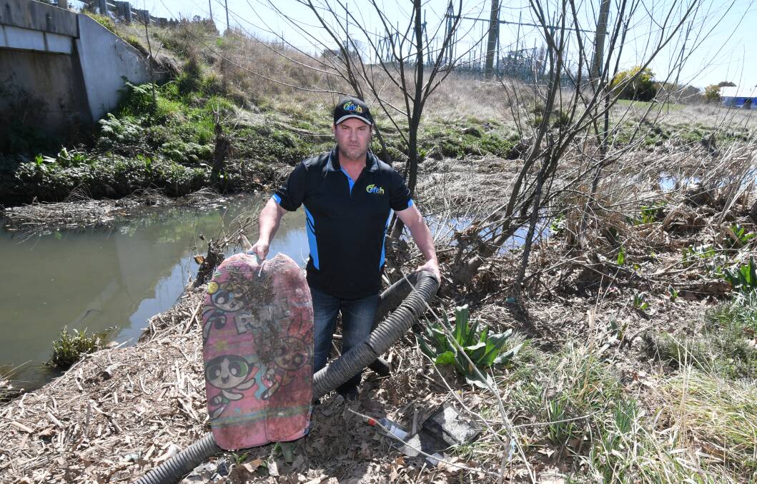 FILTH: Environmentalist Ian McLean collects some of the rubbish in the waterway near Leeds Parade which is beyond the gross pollutant trap. Photo: JUDE KEOGH 0913jkrubbish3