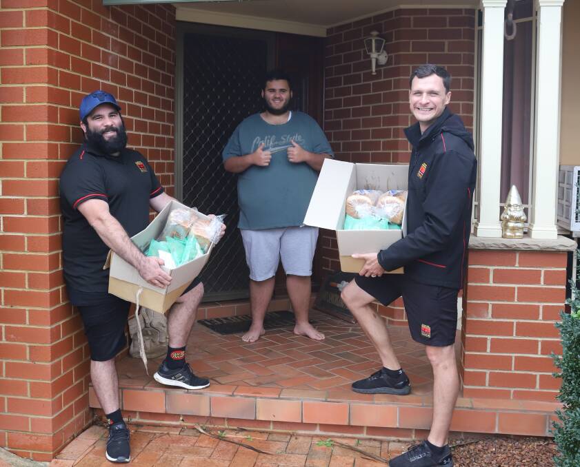 DOORSTEP DELIVERY: Tom Goolagong and Austen Logan deliver free food to a happy Kyran Toomey in Orange on Monday. Photo: CARLA FREEDMAN