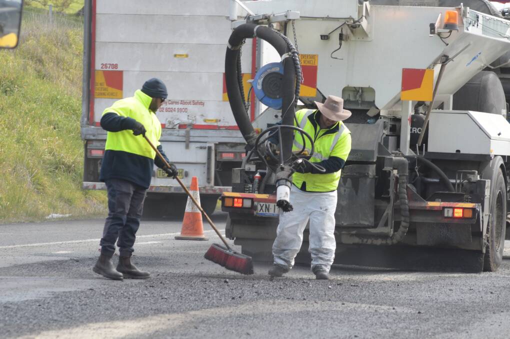 BLAST IT: Clint Murphy and Rhys Williams use the jet-patcher to repair potholes on the Northern Distributor Road on Tuesday after August's wet weather. Photo: JUDE KEOGH