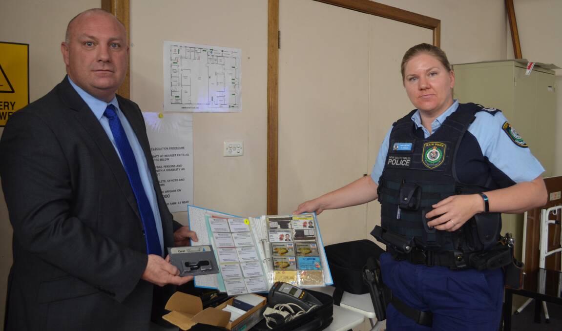 TOOLS OF THE TRADE: Detective Senior Constable Shawn Schussler and Senior Constable Nikki Hodge with fake credit cards and card skimming equipment. Photo: DAVID FITZSIMONS 1128dffraud3