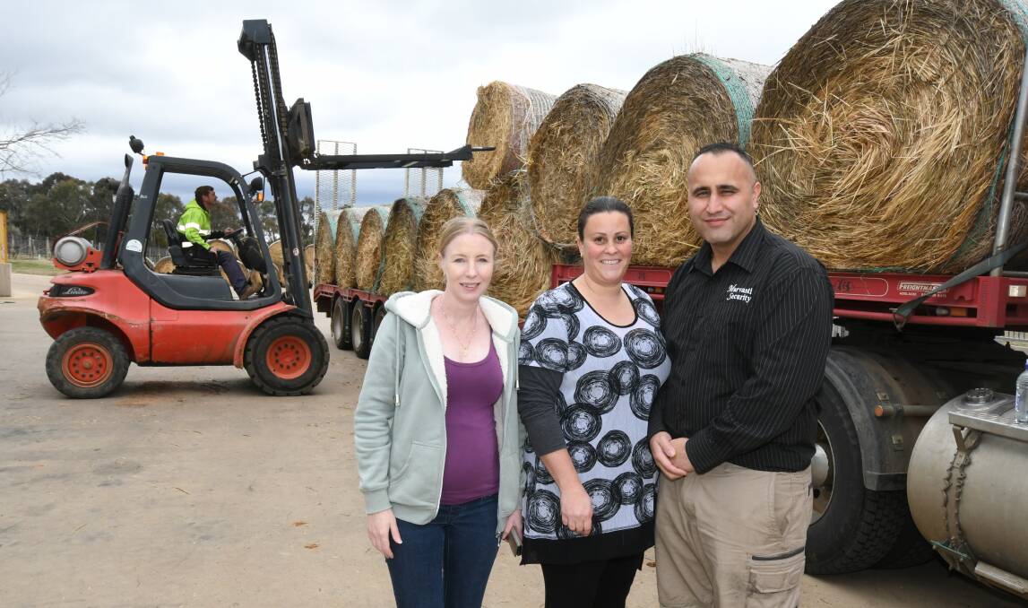 DELIVERY: Mel Flannery with Rebecca and Sina Marvasti as Jamie Ferry unloads the hay brought from Albury. Photo: JUDE KEOGH 0906jkhay4