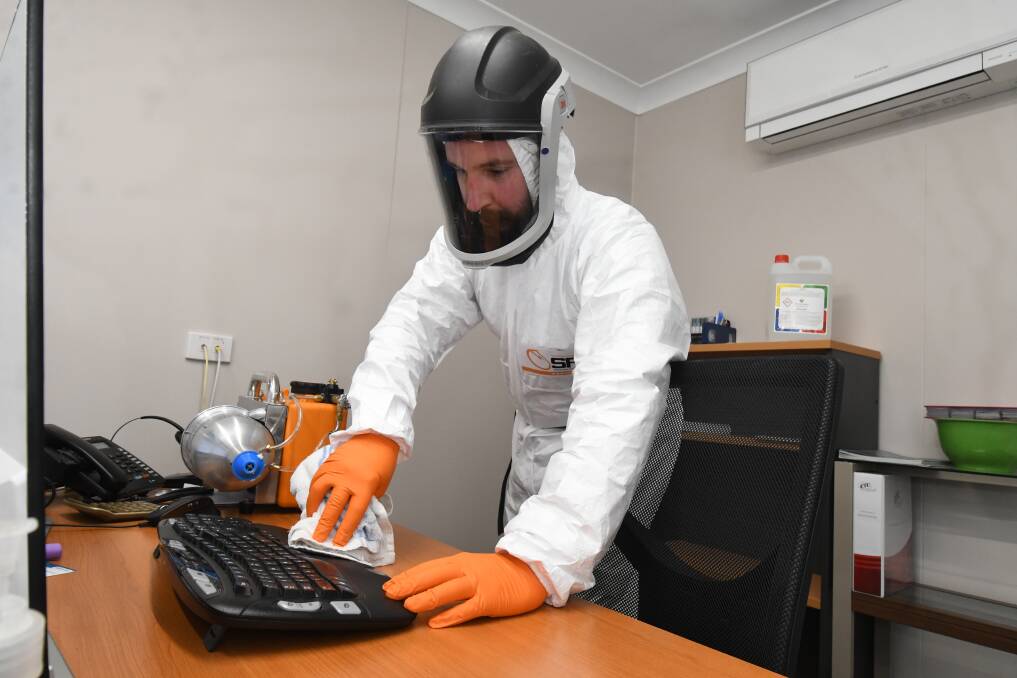 SAFETY FIRST: McArdles technician Daniel Taurins cleans down a work station as part of the company's coronavirus cleaning service. Photo: JUDE KEOGH