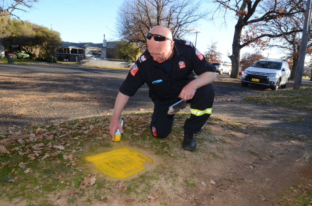 LOCATION: Senior fire fighter Brian Webster sprays yellow paint on hydrant cover. Photo: JUDE KEOGH