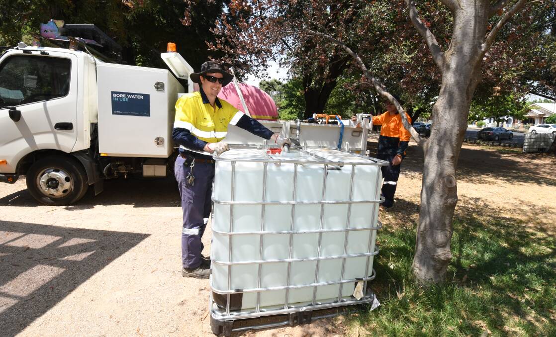 KEEPING TREES ALIVE: Council staff Phil Tiefel and Craig Delaney water trees in Cook Park using bore water. Photo: JUDE KEOGH 