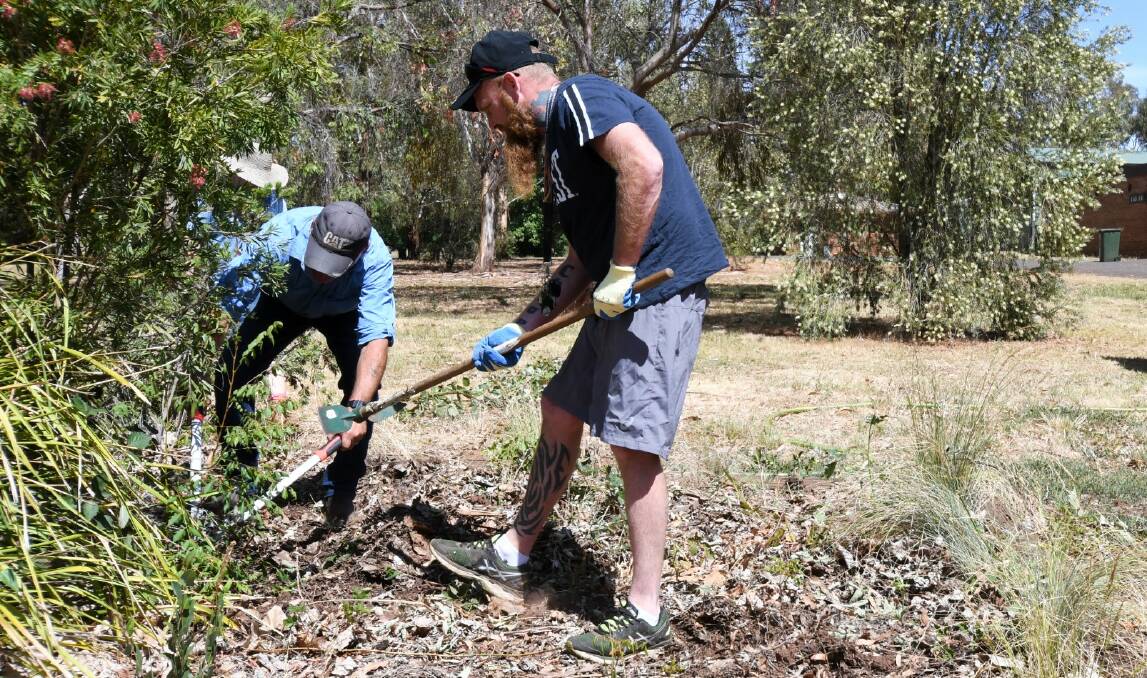 HARD YAKKA: Volunteers chop out weeds from a garden at the lake. Photo: CARLA FREEDMAN