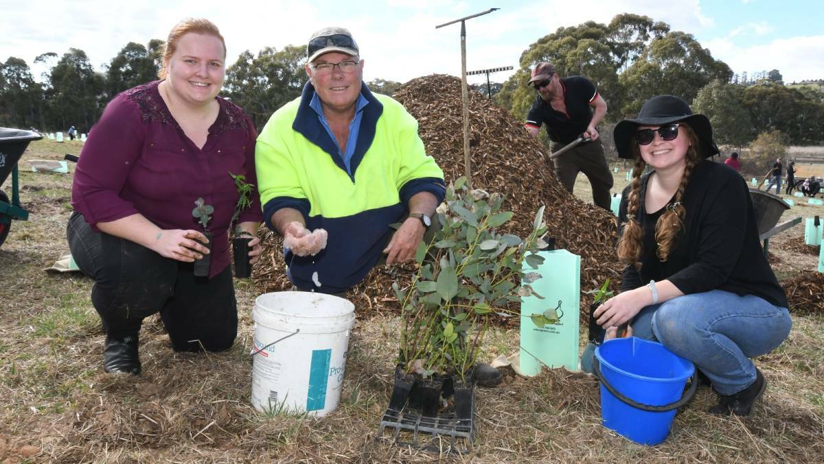 LAKE CARE: Bill Josh shows Heather Lean and Lauren Slater how to use water-saving crystals at a tree planting day at Lake Canobolas. Photo: CARLA FREEDMAN
