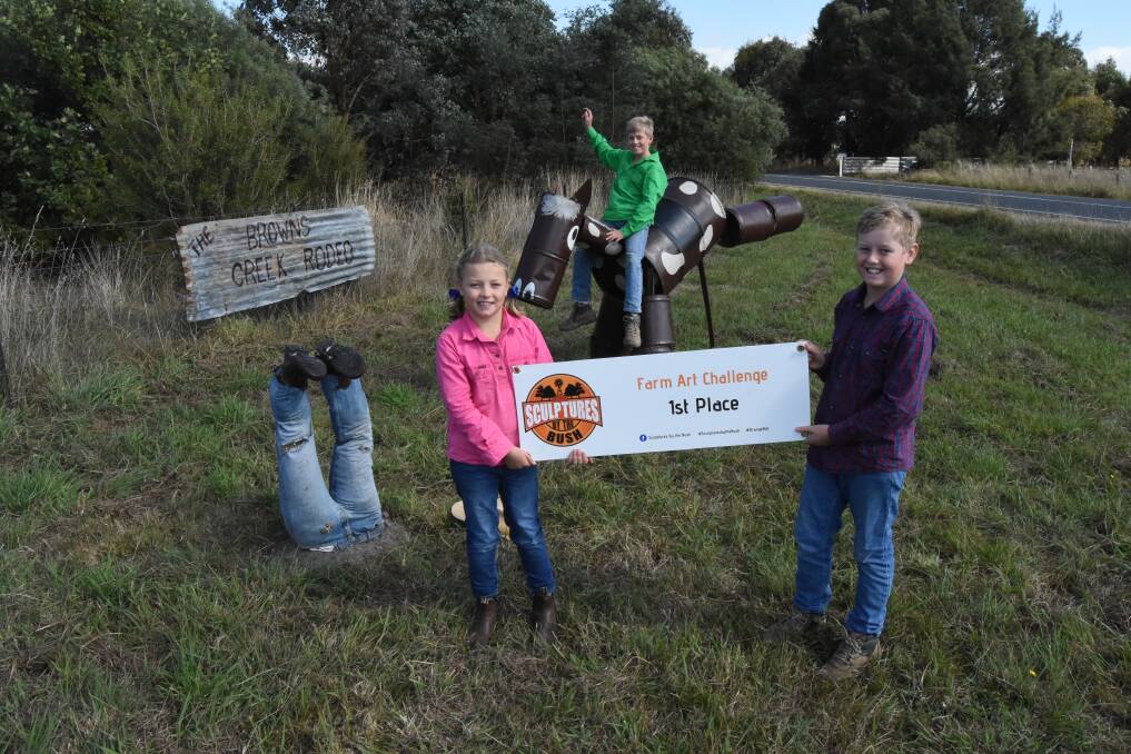 Angus Oldham was brave enough to ride the bucking bronco as his siblings Bonnie and Digby hold the winners banner. Photo: Mark Logan.