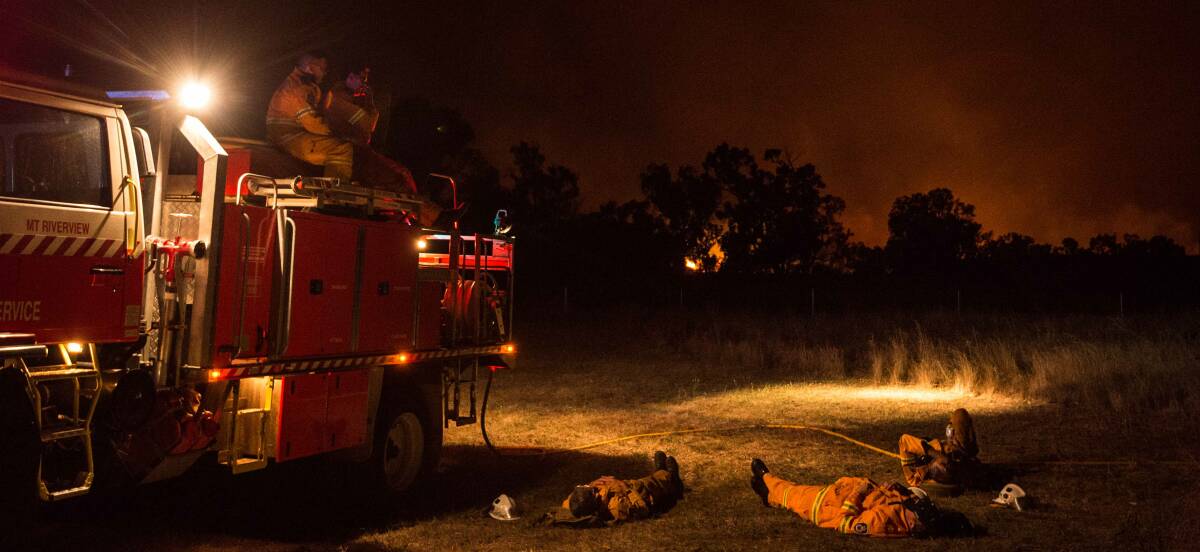 EXHAUSTED: RFS crews take a break during a battle with a large grass fire near Wollar. Firefighters from Chifley are assisting in the area. Photo: Wolter Peeters. 