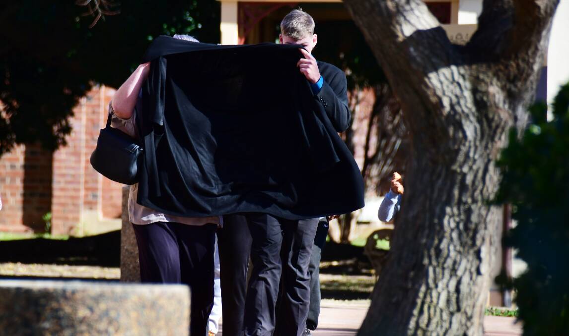 DUCKING FOR COVER: Alleged emu plucker Jye Leslie Schultz tries to cover his face up as he leaves Dubbo court. 