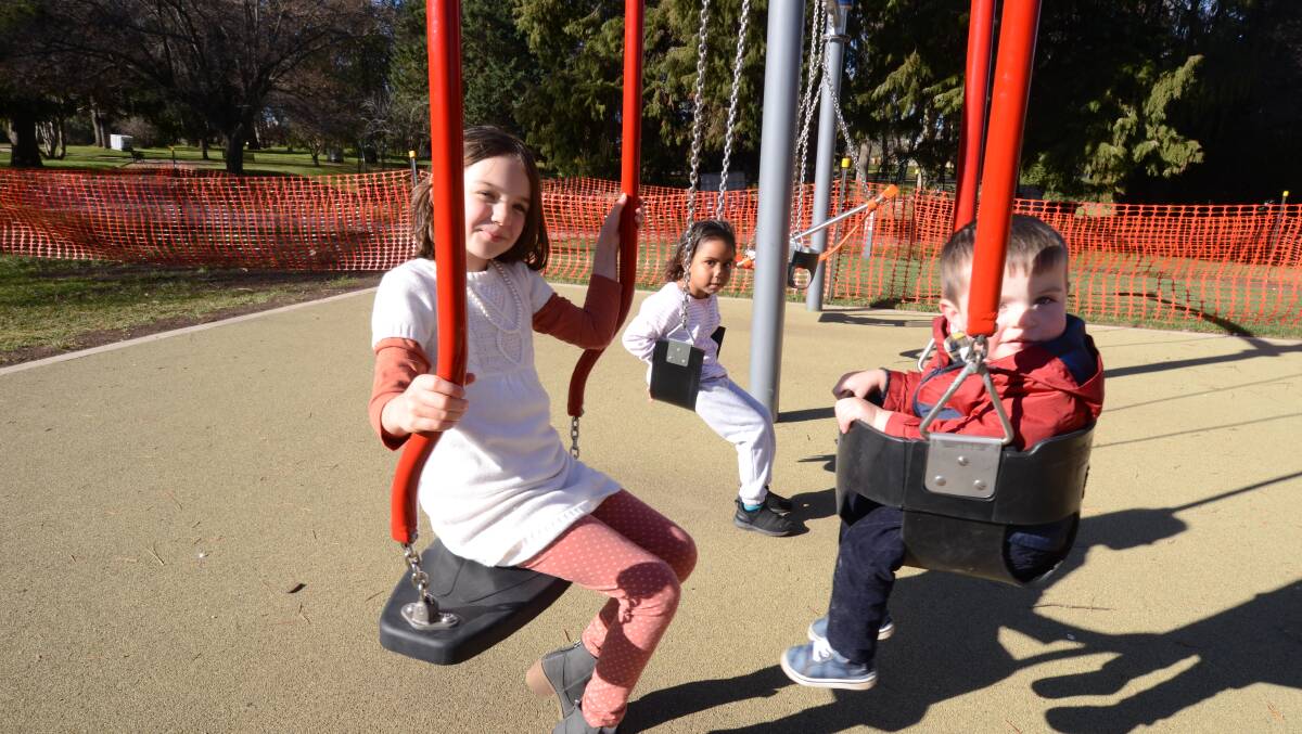 SWING SET: Orange children Eloise Thurlby, Mahalia Edwards and Lorcan Thurlby play on the new play equipment at Cook Park. Photo: JUDE KEOGH