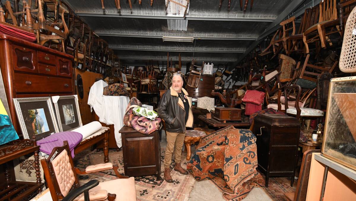 UP FOR GRABS: Steven Archer in the middle of his collection of early Colonial Australian furniture and original art which he will be auctioning off Sunday. Photo: JUDE KEOGH