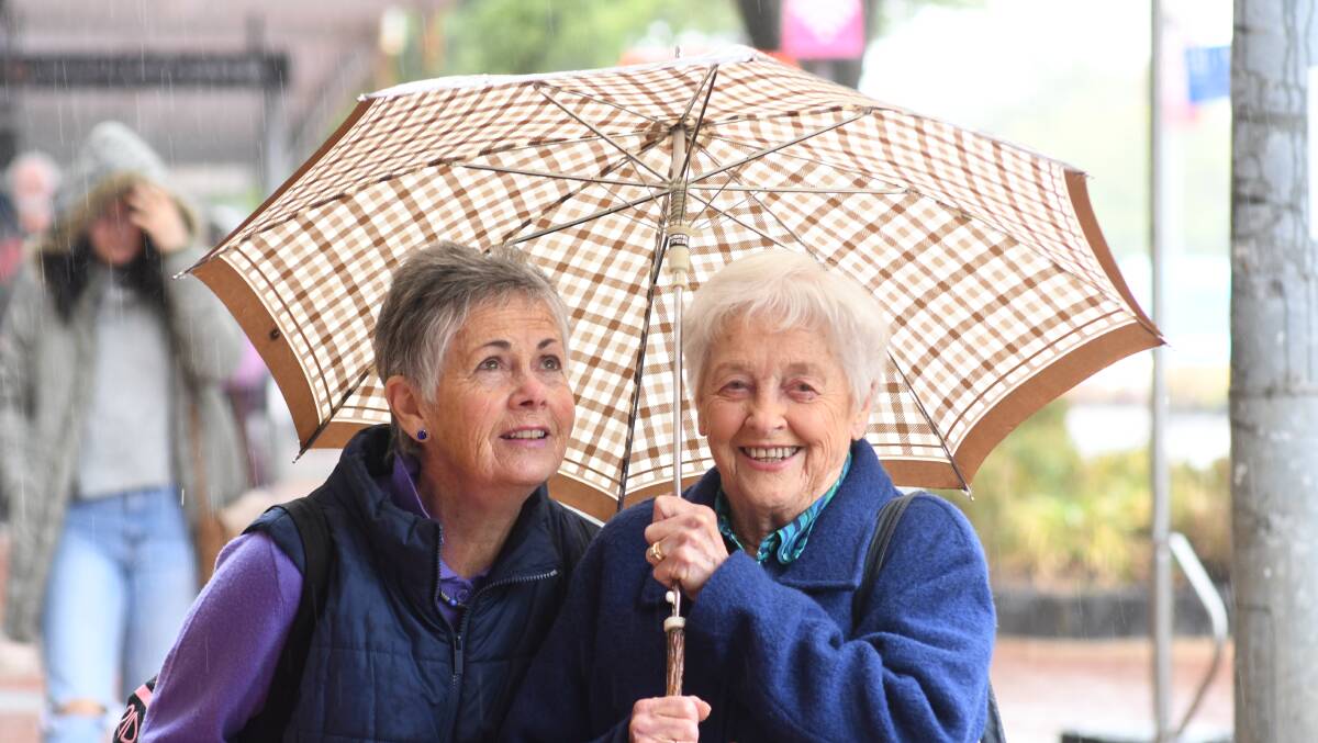GOOD BROLLY WEATHER: Robin Thompson and Gwenda Garde were well prepared for the wintery start to summer Orange enjoyed on Monday. Photo: JUDE KEOGH