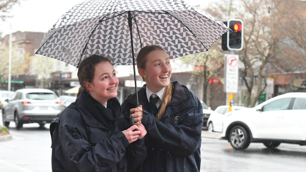 DOWN IT COMES: Alex Williams and Emily L'Estrange take refuge under an umbrella as the rain tumbles down on Summer Street. Photo: JUDE KEOGH