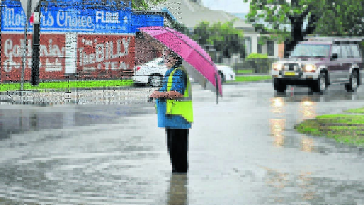 GET OUT YOUR BROLLIES: Peter Jones stands at the flooding corner of Byng and McLachlan streets in 2015. Heavy rain is predicted for Monday afternoon. 