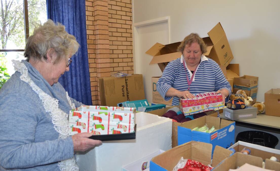 Joy Crowe and Jenny Abbott fill shoe boxes with items to give to for 10 to 14-year-old boys.  