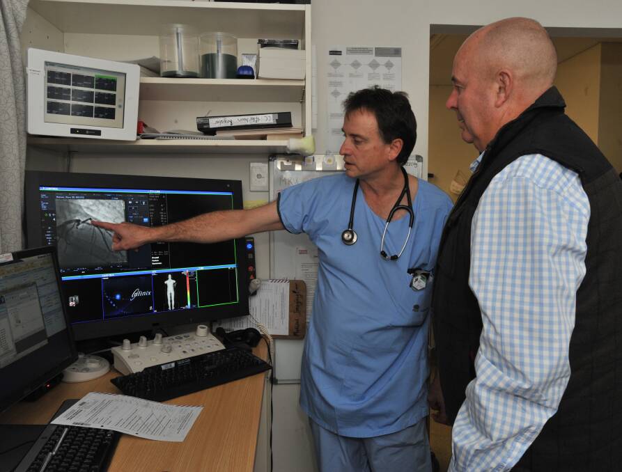 VISUAL EXPLANATION: Operating surgeon Dr David Amos shows Steve Hamson images of his heart and the difference in his heart before and after surgery. Photo: JUDE KEOGH 0815jksteve1